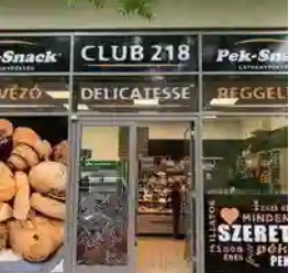 Üzlet bejárata feliratokkal, snack és delikátesz kirakatokkal, ajtó nyitva, városi utcán.